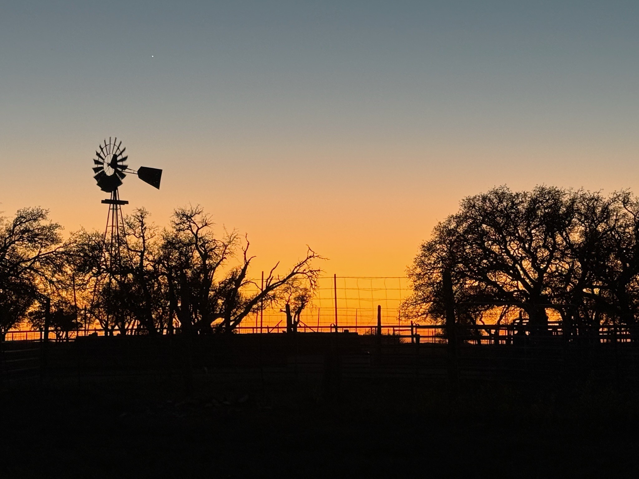 3-Wire Ranch at golden hour — windmill silhouette against Texas Hill Country sunset